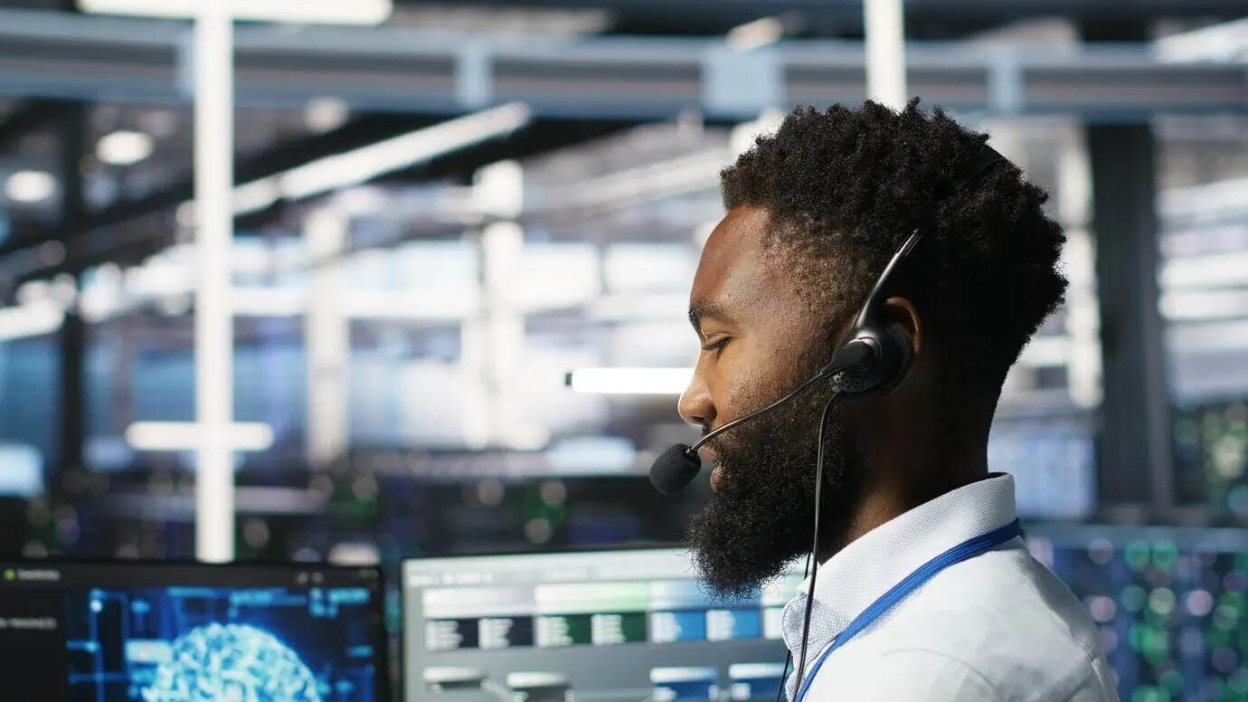 Mitarbeiter im Rechenzentrum spricht in ein Headset-Mikrofon und koordiniert Techniker.
